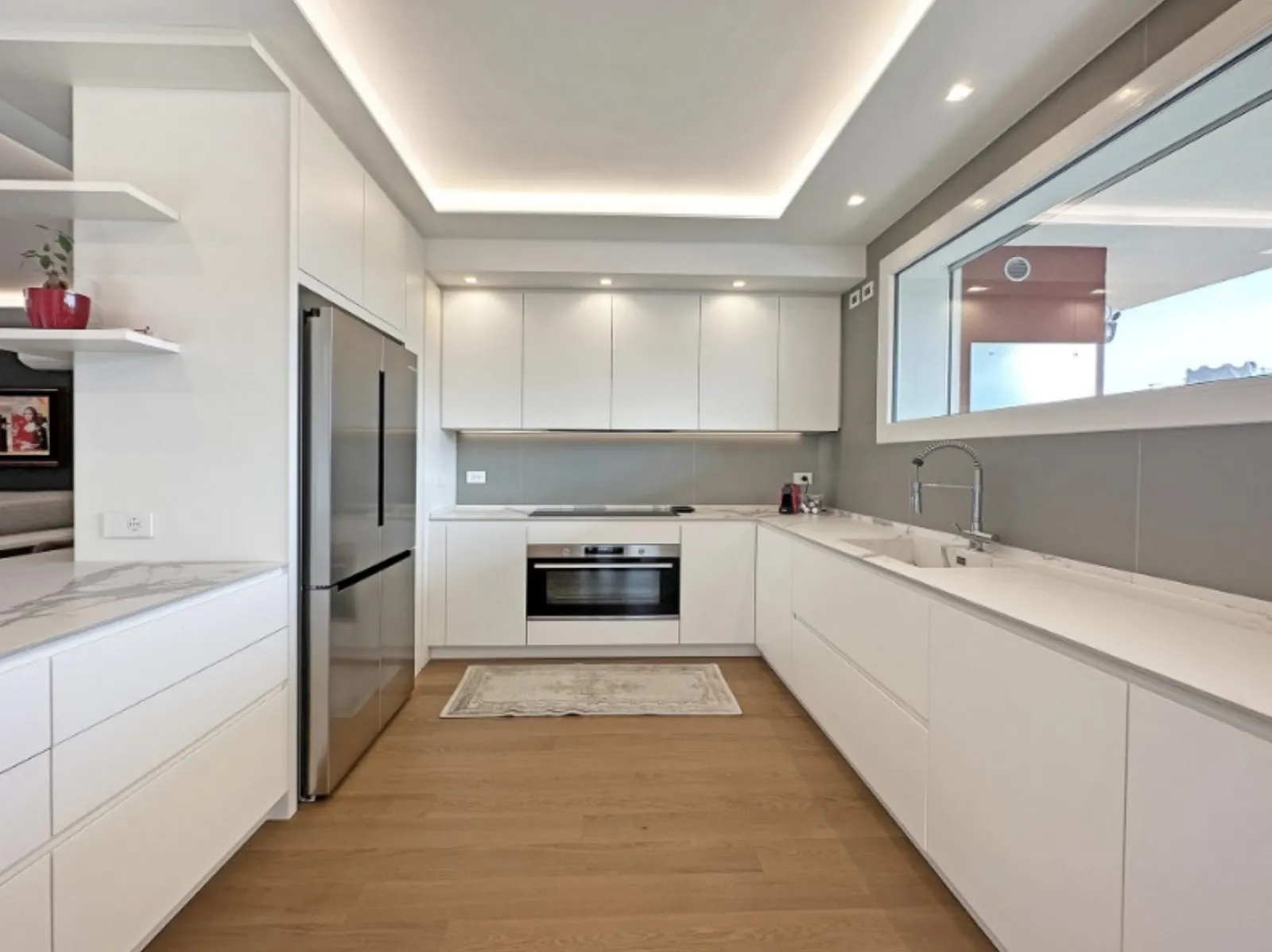 Cucina a U con grande finestra interna e top in marmo