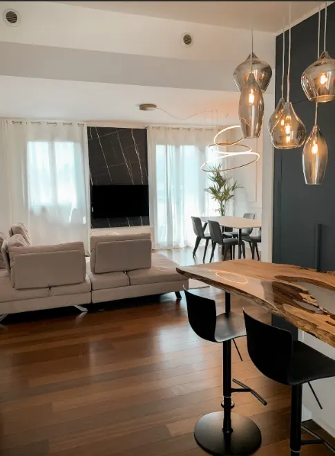 Open space con living, zona pranzo e bancone snack in legno con resina