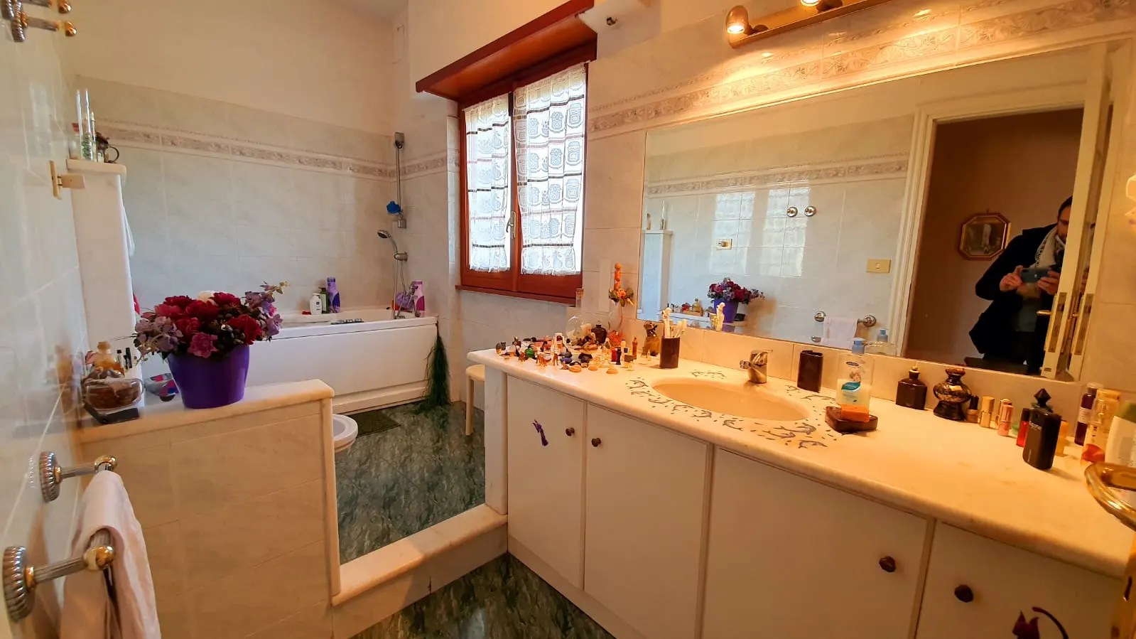 Bagno con vasca, lavabo in marmo e ampio specchio