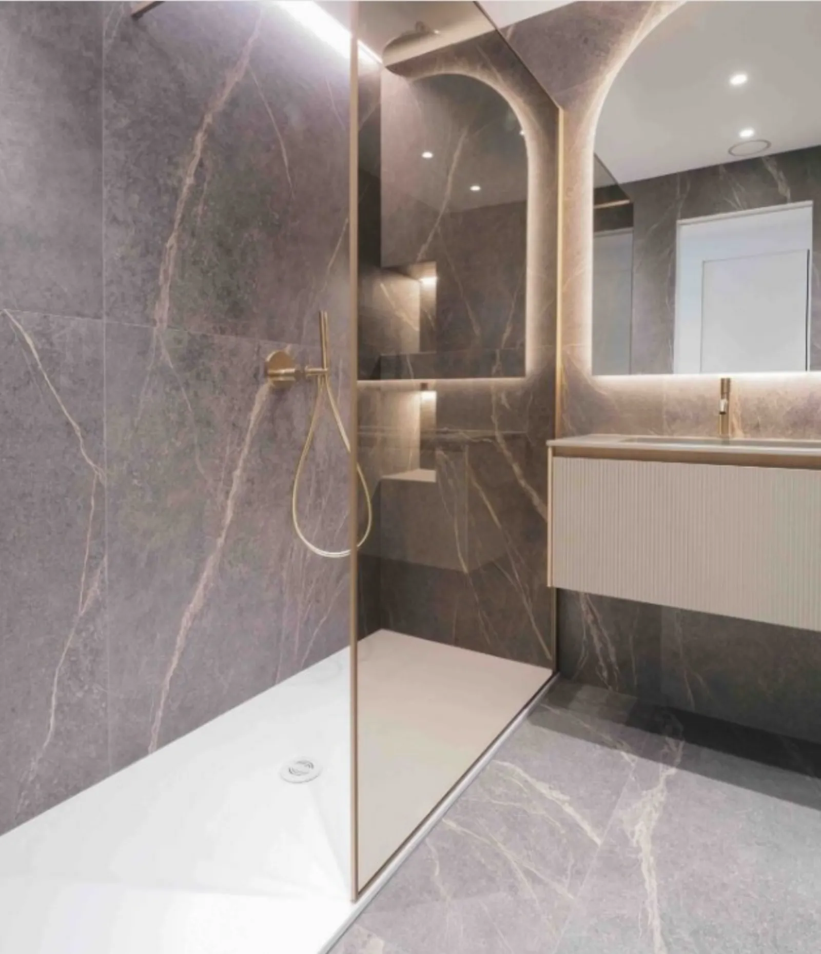 Doccia walk-in con rivestimento effetto pietra e profili dorati