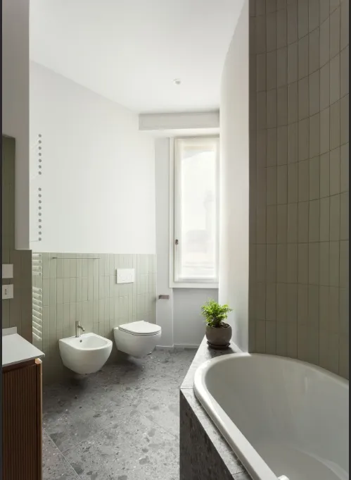 Dettaglio bagno con rivestimento verde salvia e vasca