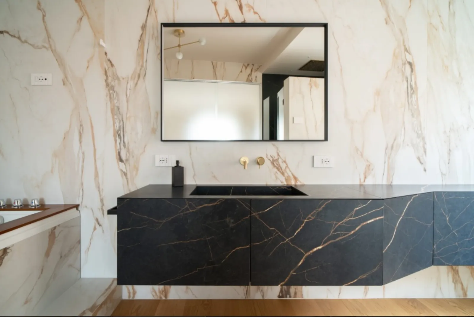 Bagno padronale con mobile in pietra venata e parete in marmo calacatta