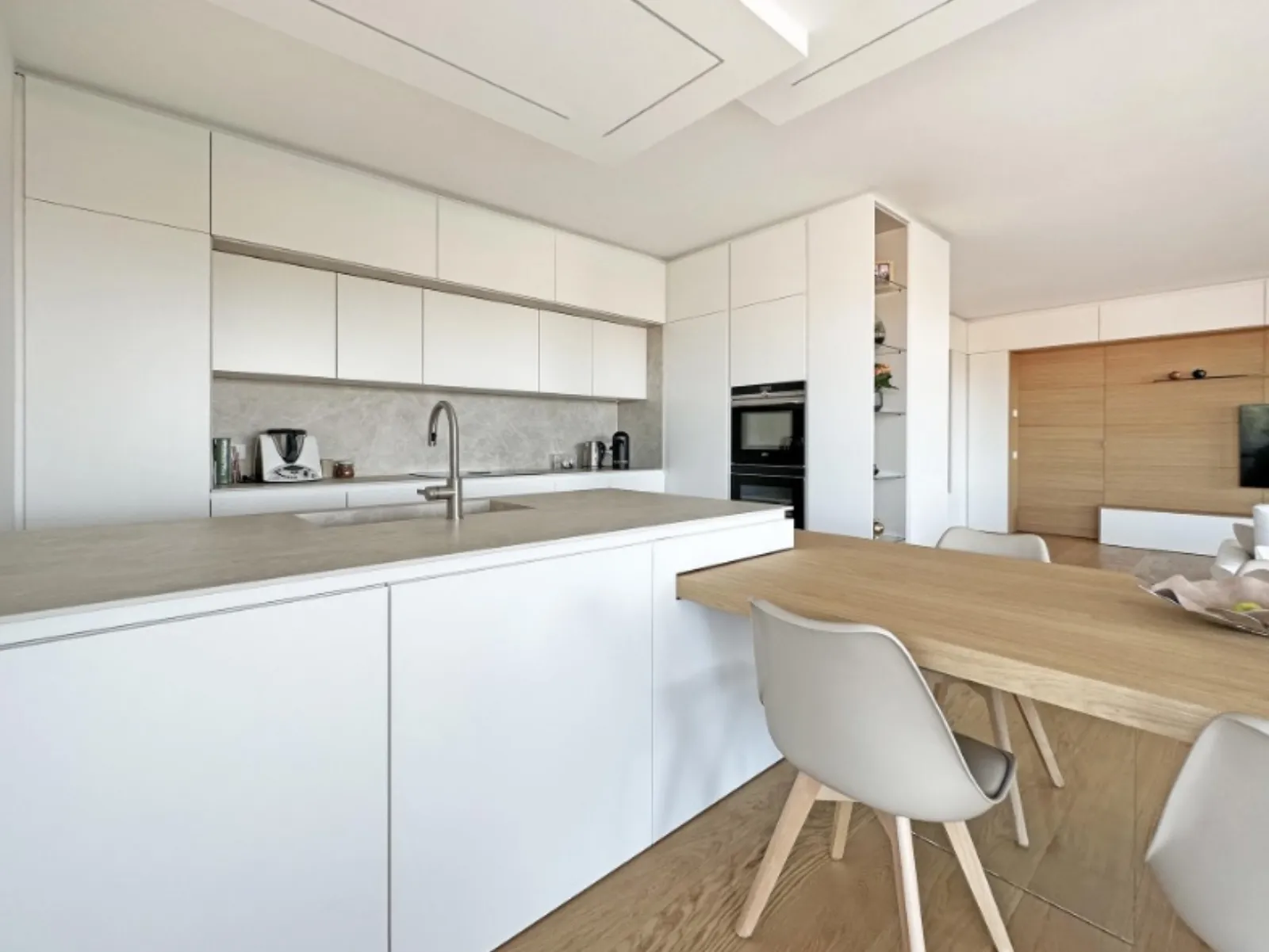 Cucina bianca con isola in pietra e piano cottura integrato