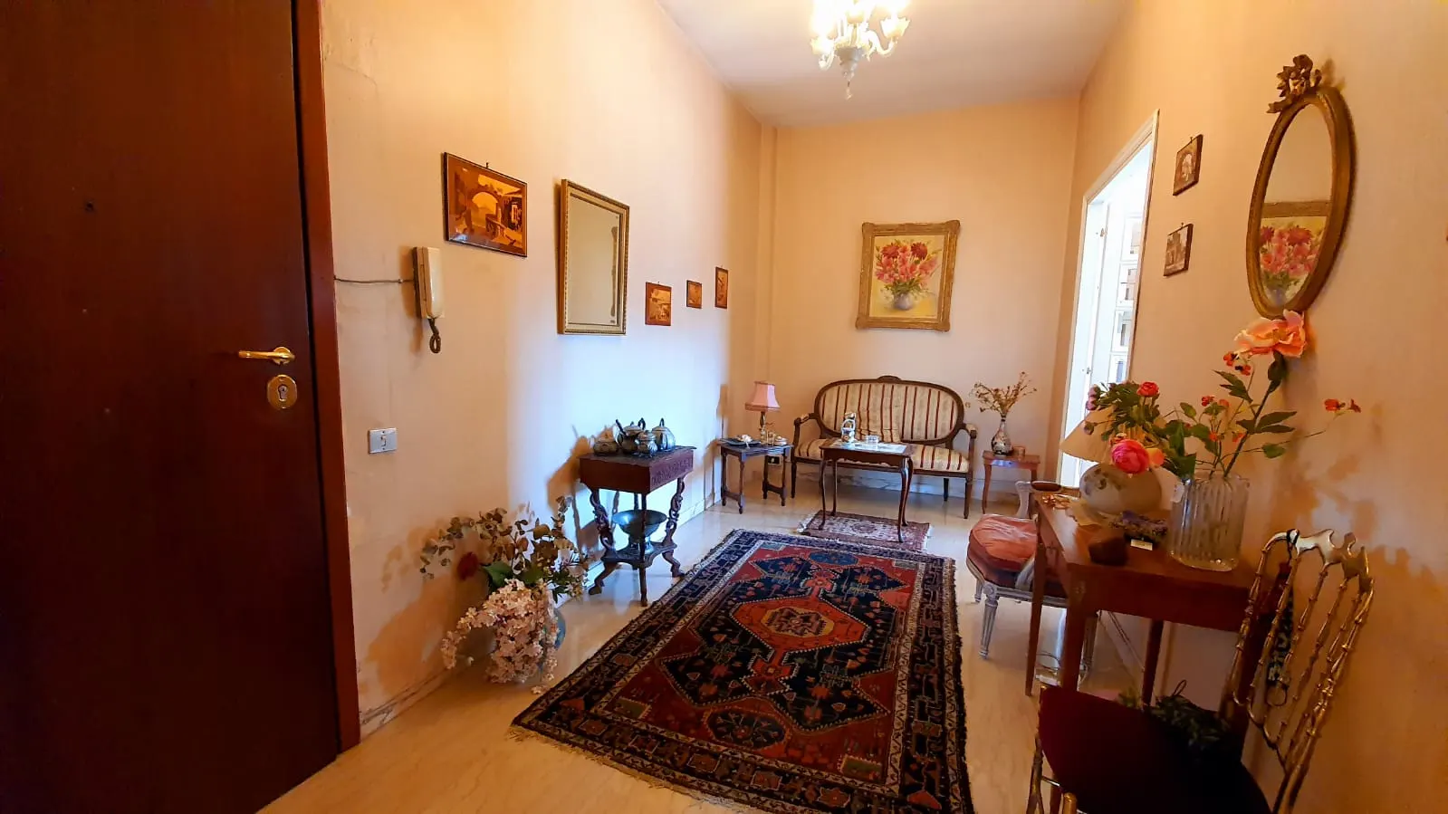 Ingresso con porta in legno, lampadario in vetro e arredi d'epoca