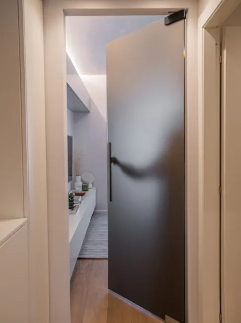 Ingresso con porta a bilico in metallo scuro e affaccio sul bagno