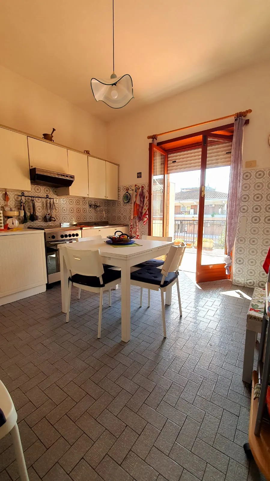 Cucina abitabile con lampada a sospensione in vetro e accesso al terrazzo