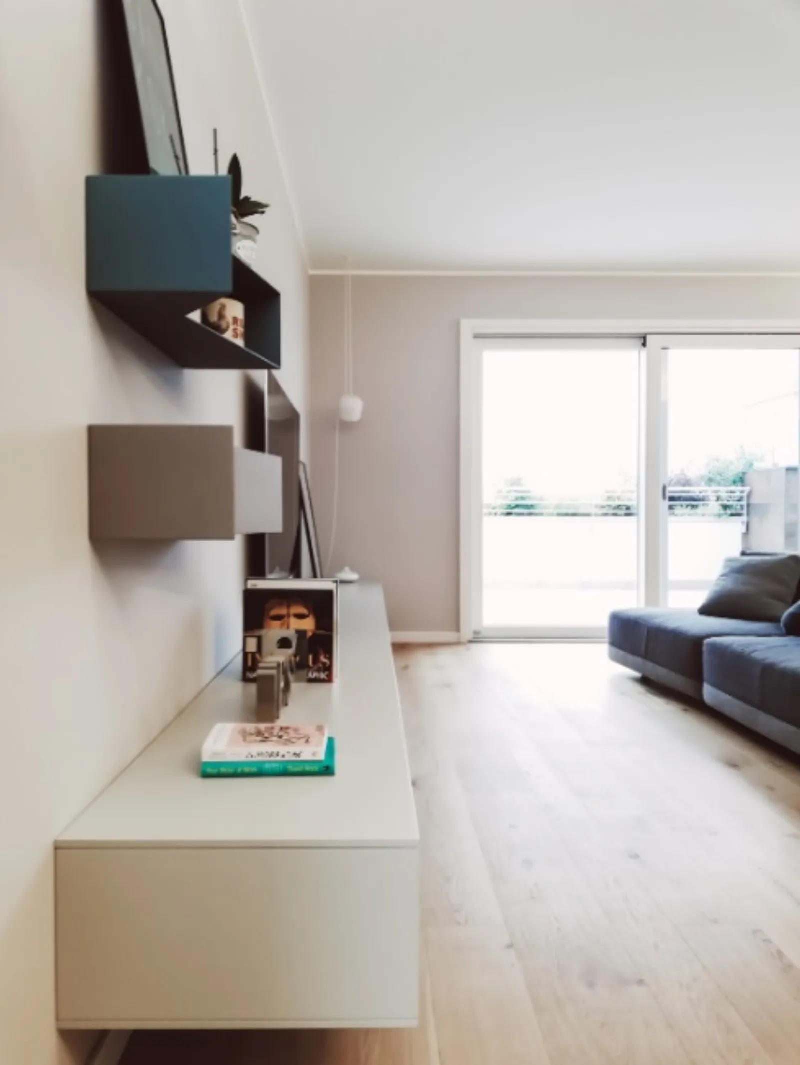 Parete TV con pensili colorati blu e tortora e mobile bianco sospeso