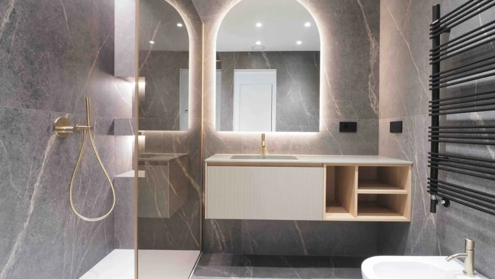 Bagno in pietra grigia con specchio ad arco retroilluminato e rubinetteria in oro satinato