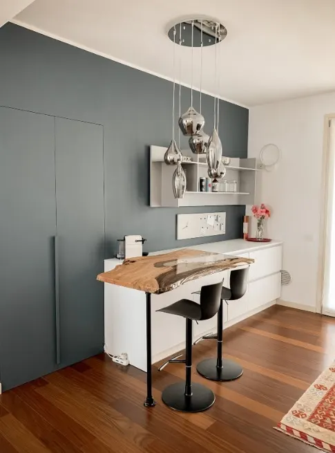 Cucina con isola snack, parete grigio antracite e mobili contenitori bianchi