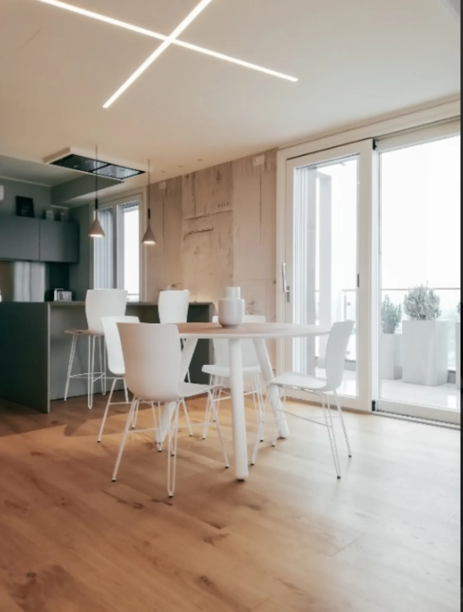 Zona pranzo con tavolo rotondo, sedie bianche e tagli di luce a soffitto