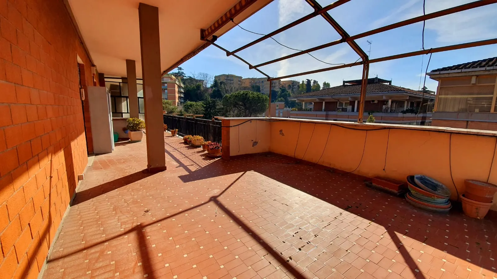 Angolo del terrazzo con pergolato in metallo e vista sui tetti del quartiere