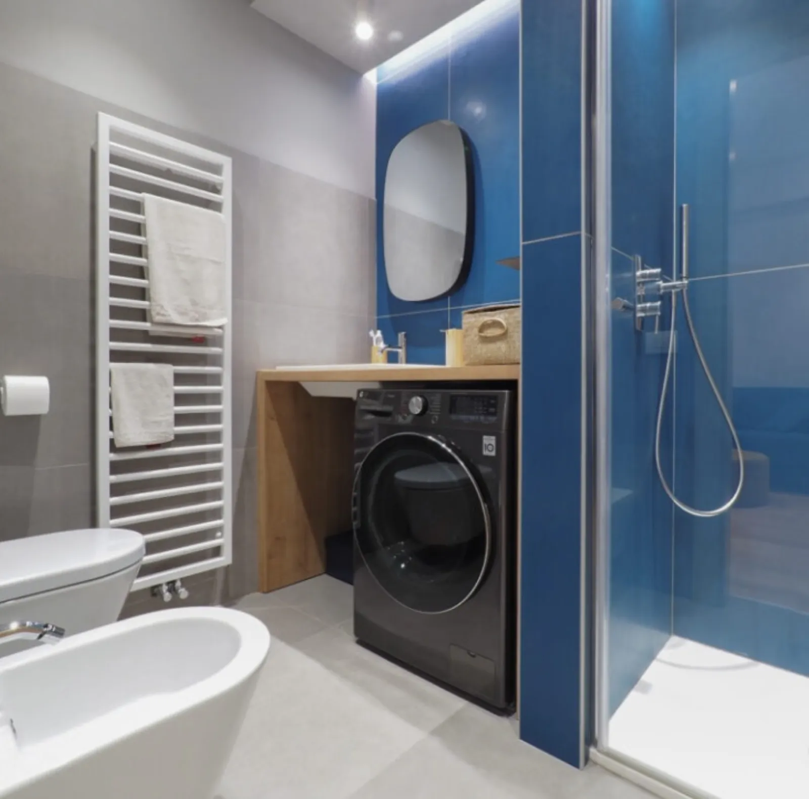 Bagno con doccia rivestita in blu e mobile in rovere su misura