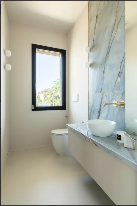 Bagno ospiti con parete in marmo blu venato e rubinetteria oro