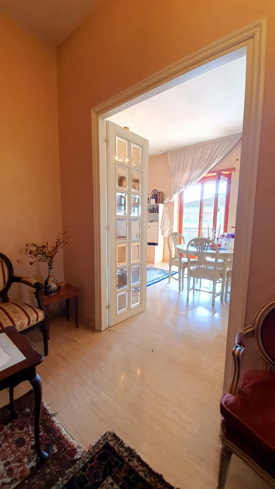Vista dall'ingresso verso la zona pranzo con porta a vetri e tappeto