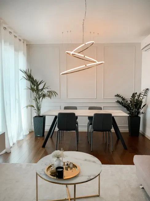 Sala da pranzo con boiserie chiara, parquet caldo e tavolino in marmo