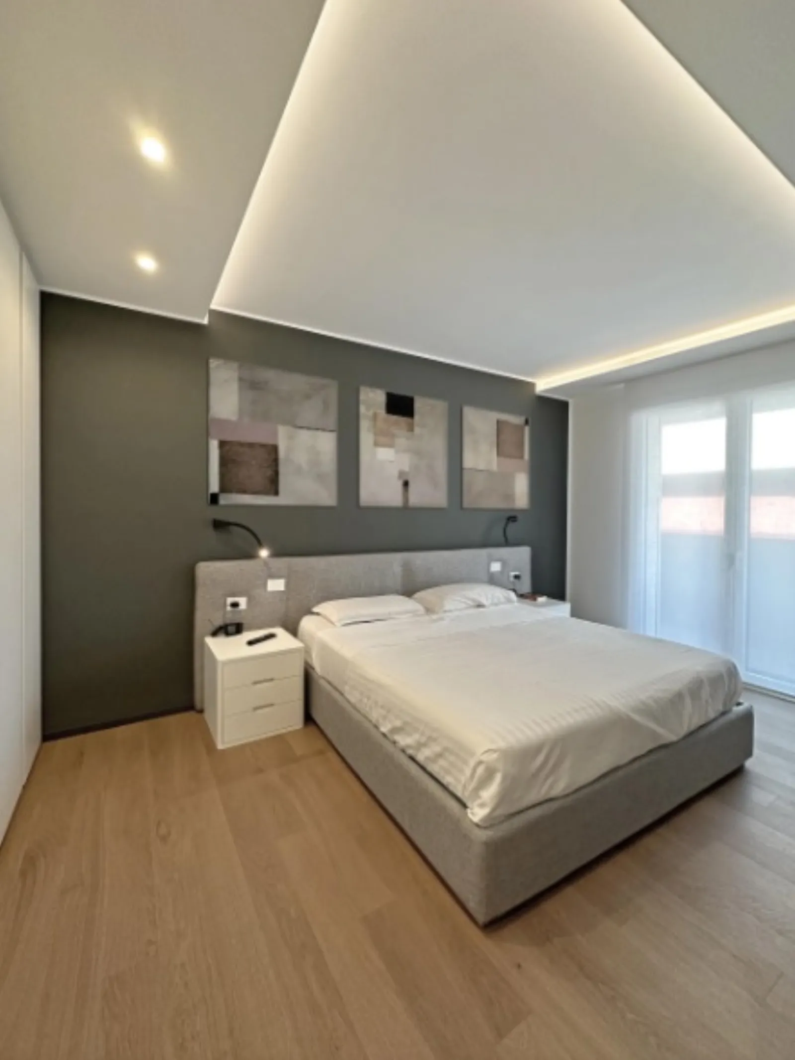 Camera da letto con testiera tessile e velatura luminosa a soffitto