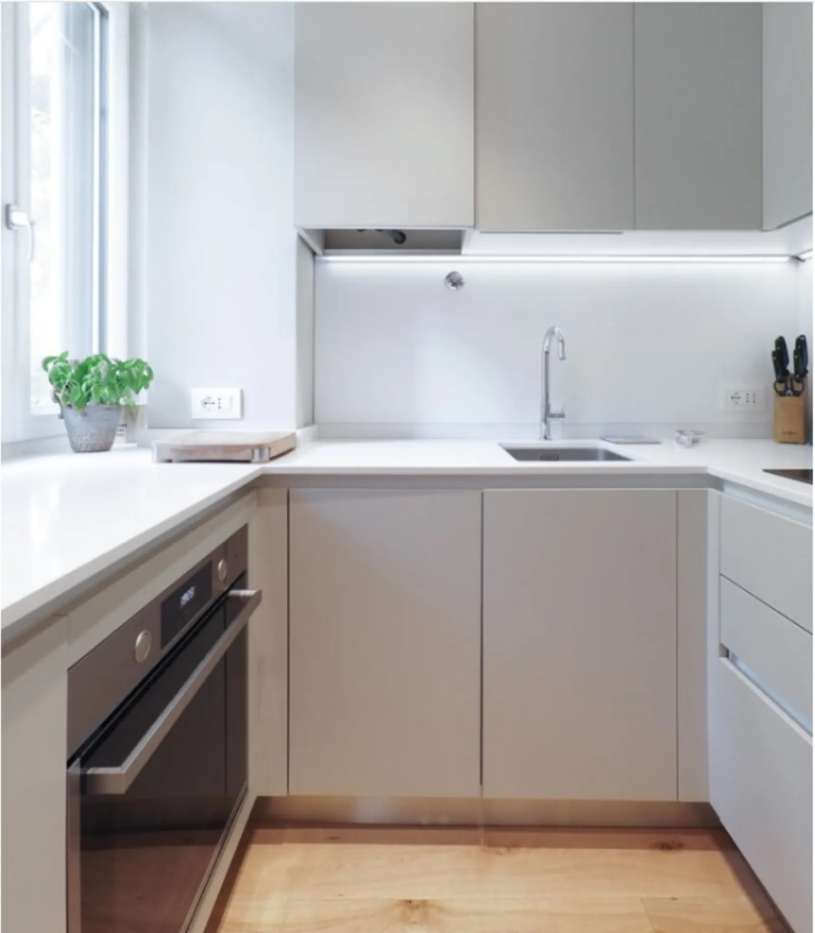 Cucina a ferro di cavallo in laccato grigio chiaro con piano bianco