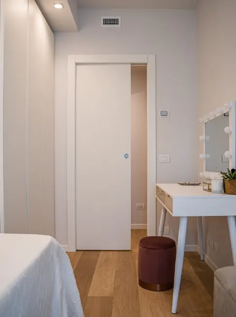 Cameretta con consolle make-up illuminata, pouf bordeaux e porta a scrigno